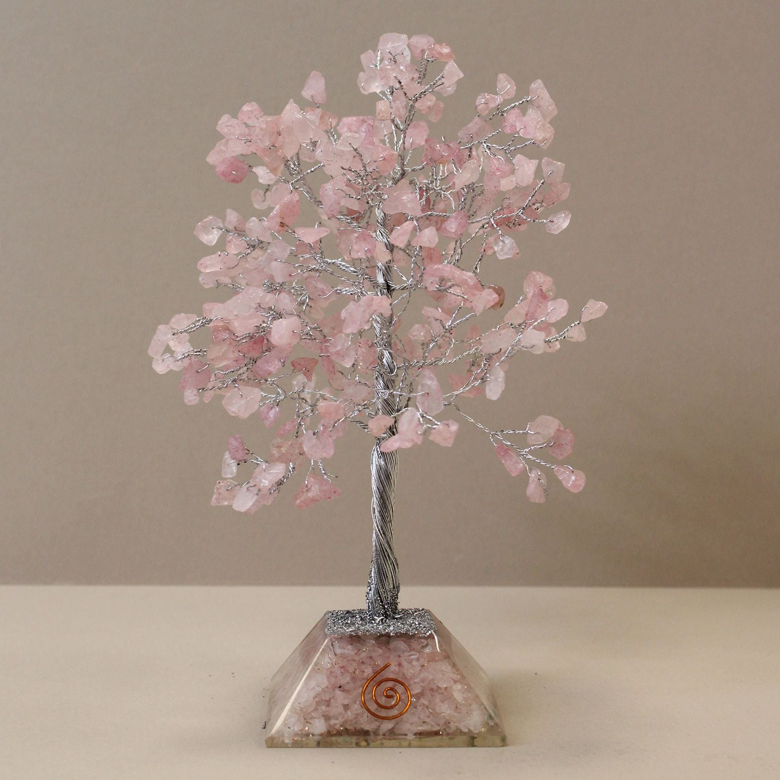 Apportez une touche douce et spirituelle à votre intérieur avec cet arbre en quartz rose avec socle en orgonite. Composé de 320 pierres naturelles, il séduit par son allure généreuse, son esthétique minérale et sa présence décorative apaisante.