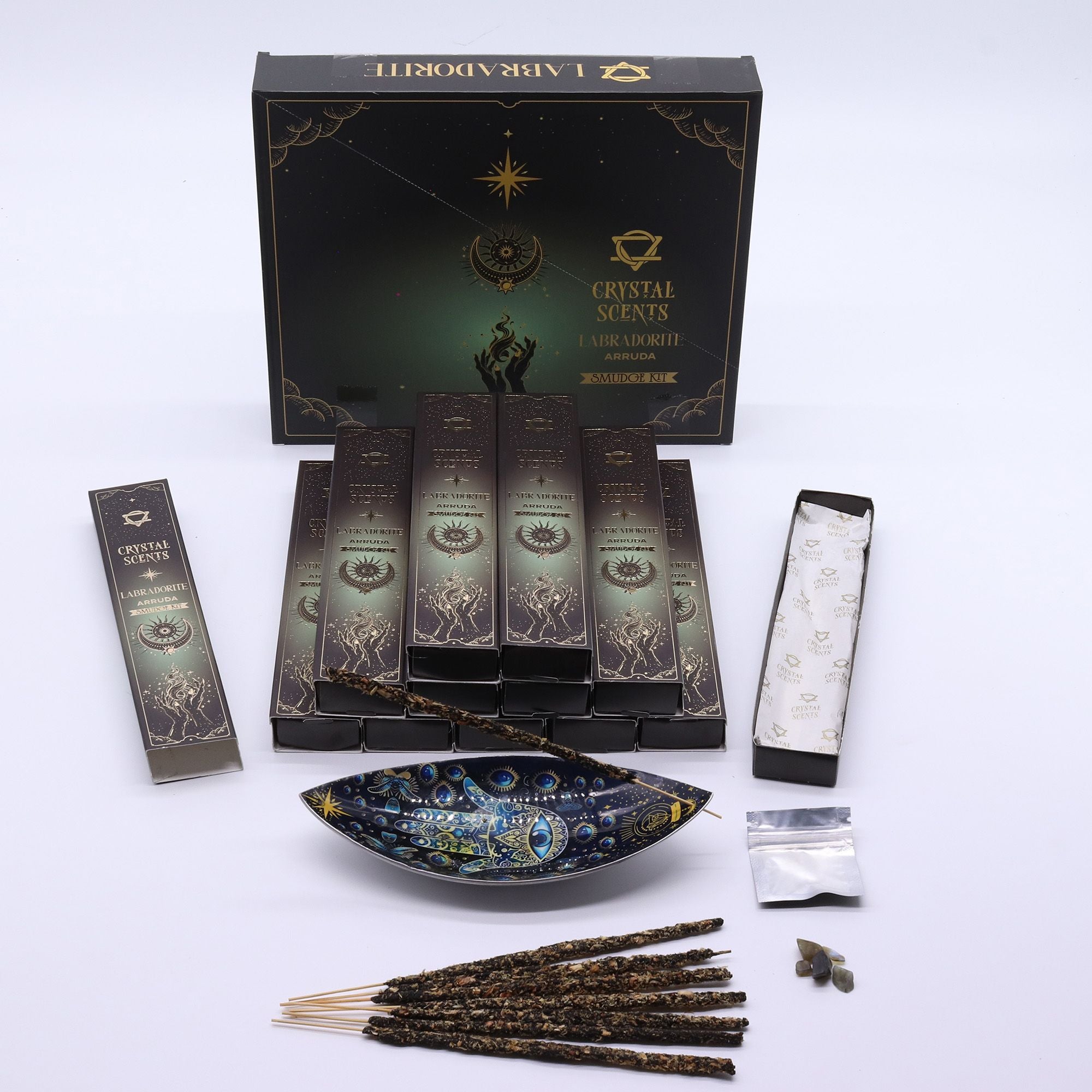Encens Smudge Arruda accompagné d’éclats de Labradorite naturelle. La boîte contient 10 bâtons d’environ 20 cm, fabriqués à la main en Inde et présentés dans un étui cartonné vert profond au style céleste.