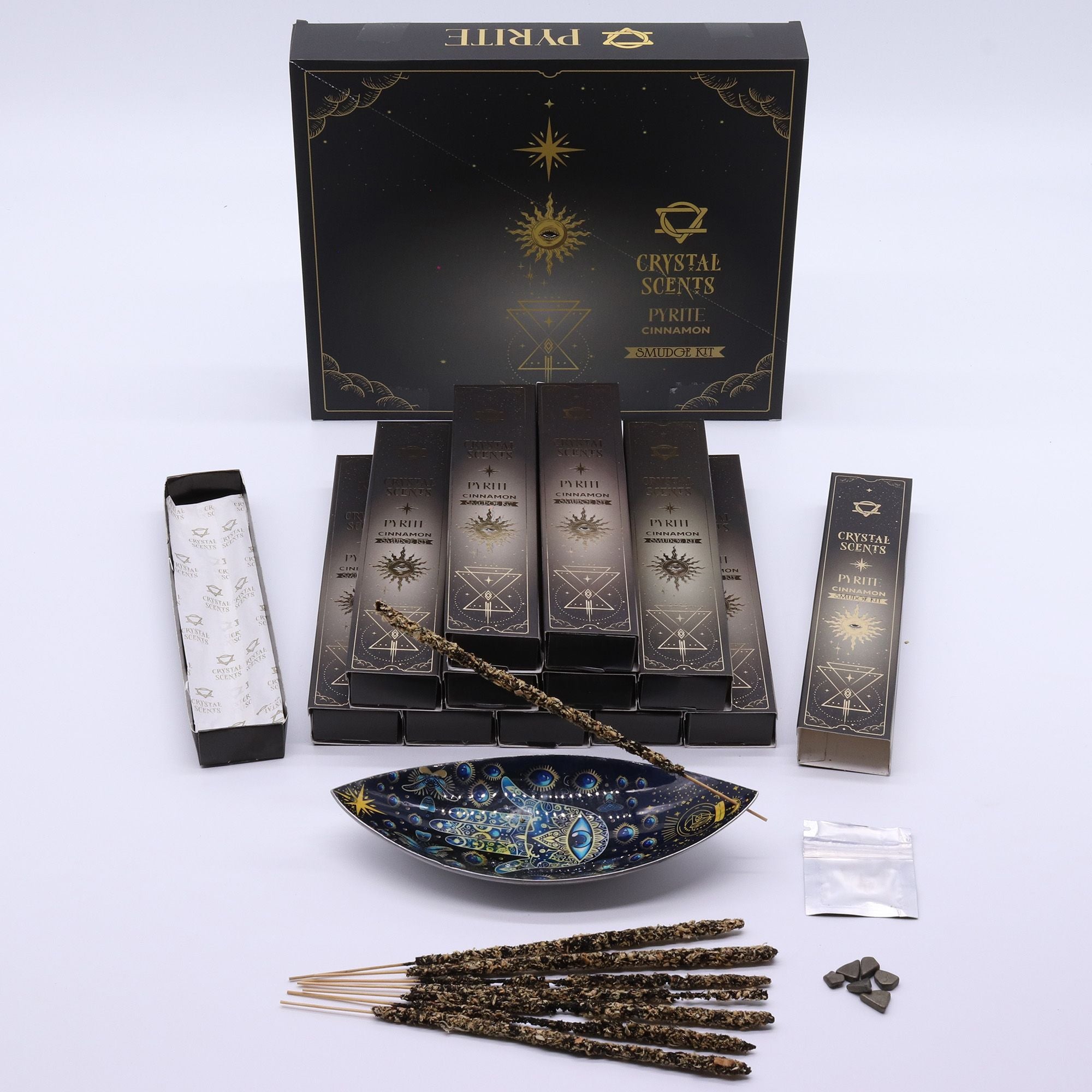 Encens Smudge Cannelle accompagné d’éclats de Pyrite naturelle. La boîte contient 10 bâtons d’environ 20 cm, fabriqués à la main en Inde et présentés dans un étui cartonné sombre au thème céleste.