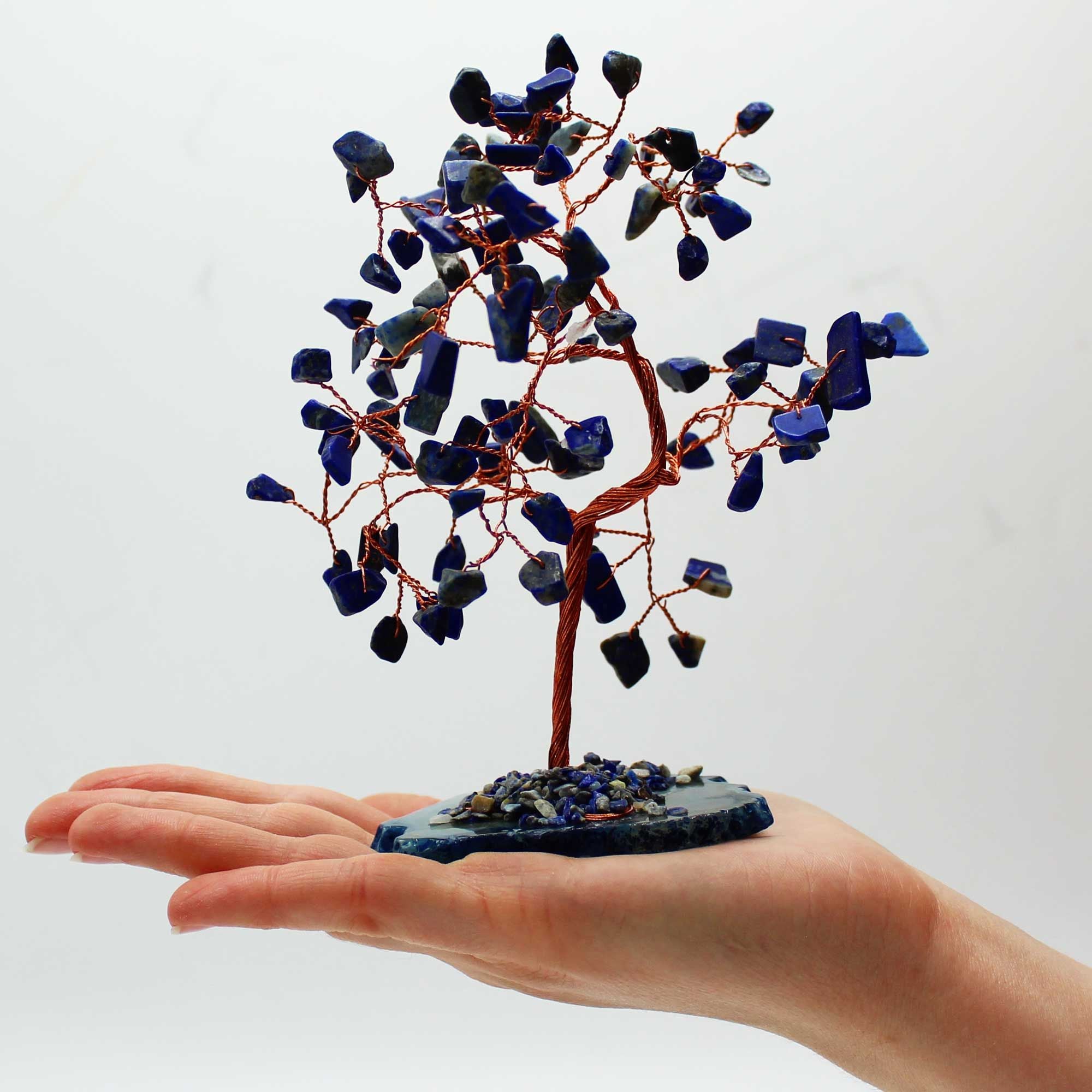 Apportez une touche minérale et apaisante à votre intérieur avec ce grand arbre en sodalite sur socle en agate bleue. Orné de 100 pierres naturelles, il séduit par son allure élégante, son style artisanal et son esthétique spirituelle.
