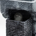 Gros plan d’une fontaine d’intérieur avec boule cristal, texture effet pierre et finitions sculptées.