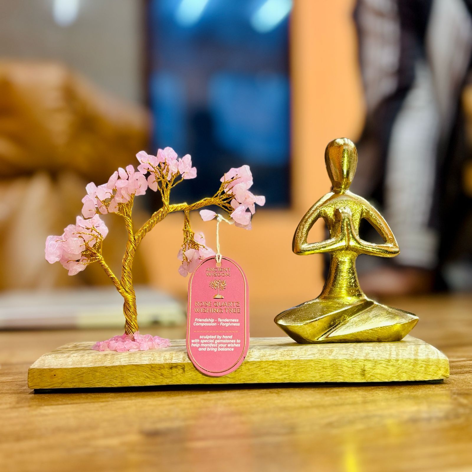 Apportez une touche spirituelle et poétique à votre intérieur avec ce jardin yoga en quartz rose. Composé d’un arbre incliné en pierres naturelles, d’une figurine dorée en posture Namaste et d’un socle en bois, il crée une ambiance douce, harmonieuse et profondément apaisante.