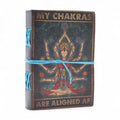 Journal/grimoire en cuir imprimé avec motif Chakras et texte “My Chakras Are Aligned AF”. Il contient 200 pages blanches en papier, idéales pour écrire, dessiner ou noter ses inspirations.
