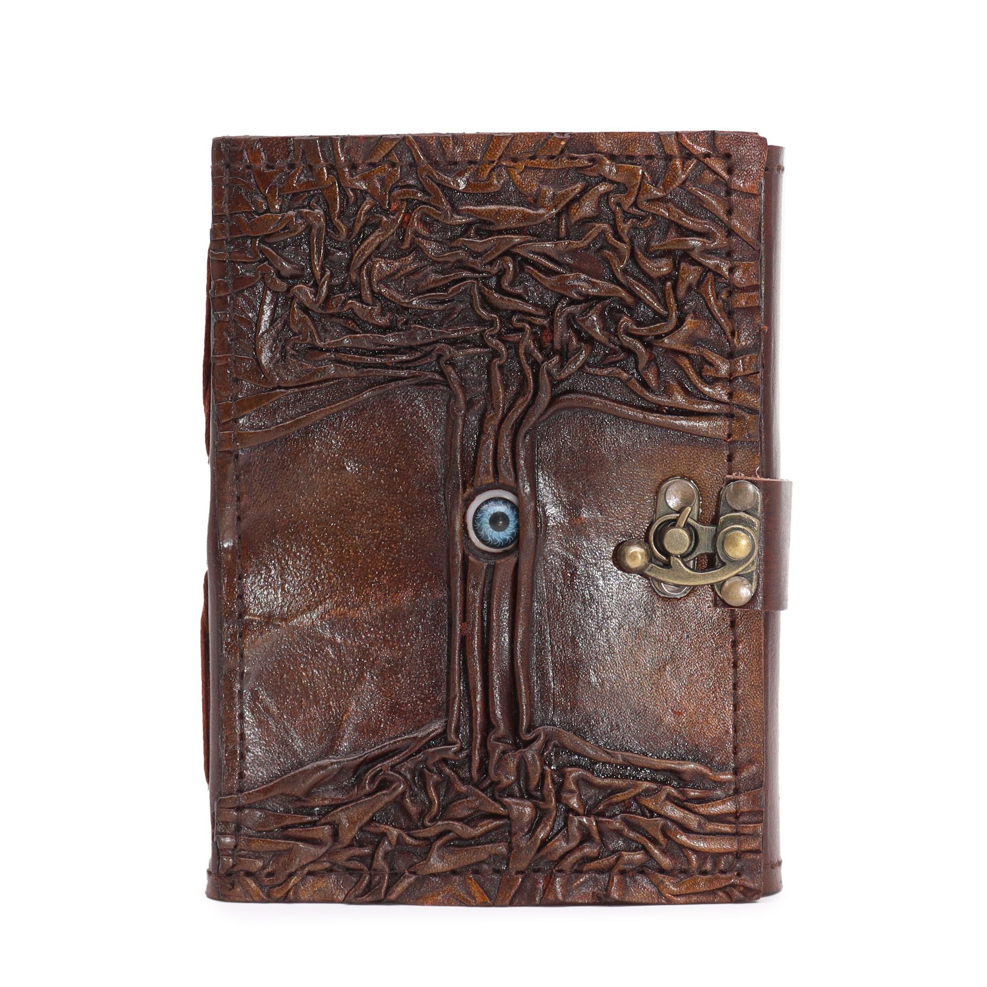 Journal/grimoire en cuir noir et brun, décoré d’un motif Œil protecteur. Il contient 160 pages en papier à bords irréguliers, dans un format compact et pratique.