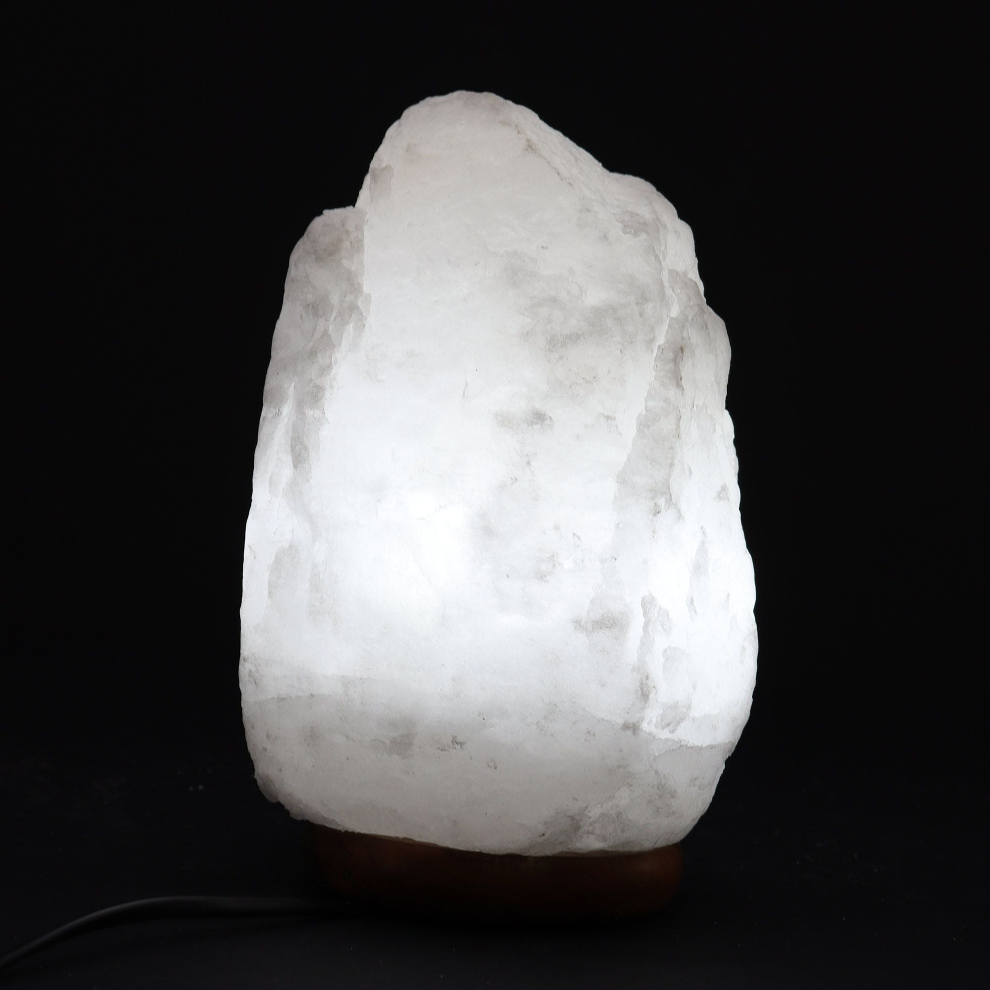 Lampe en sel de l’Himalaya blanche allumée, avec socle en bois, idéale pour une ambiance douce et apaisante.