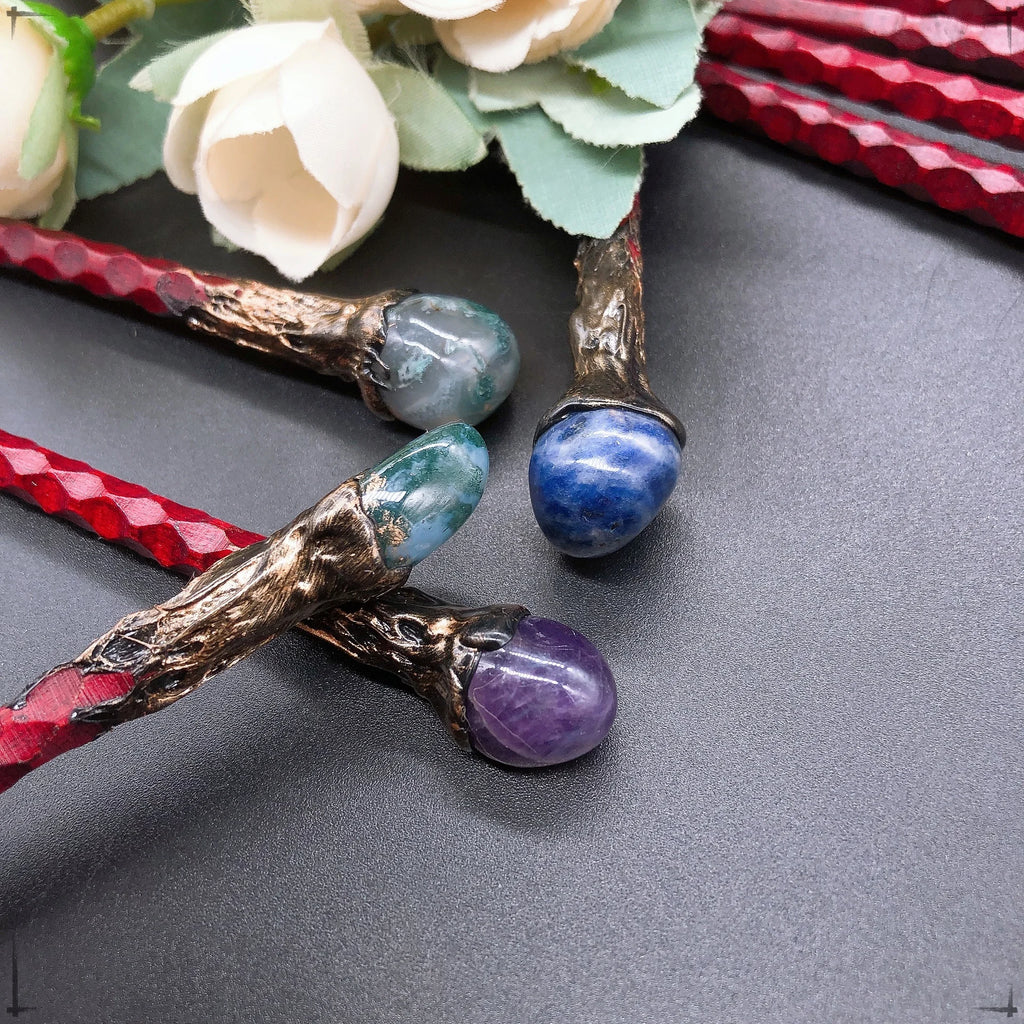 Gros plan sur les baguettes magiques avec des pierres comme la labradorite et l'œil de tigre, disponibles chez Aemilia Mystica.