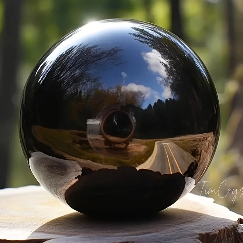 Boule en obsidienne noire naturelle polie – de 2 à 13 cm sur un support naturel, symbole de sérénité et d'harmonie, utilisée dans des espaces spirituels.