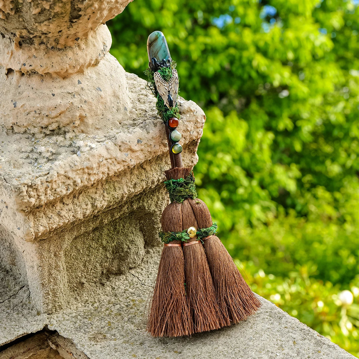Balai De Sorcière - Pointe De Cristal en pierre Naturelle, un balai de purification unique placé sur une pierre, intégrant améthyste et autres cristaux naturels pour apporter de l'énergie positive et améliorer votre espace de méditation.