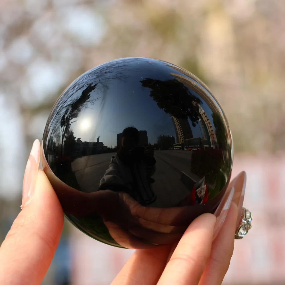 Sphère d'obsidienne noire naturelle polie – de 2 à 13 cm présentée dans la main, éclat brillant, parfaite pour la décoration feng shui et comme objet spirituel.