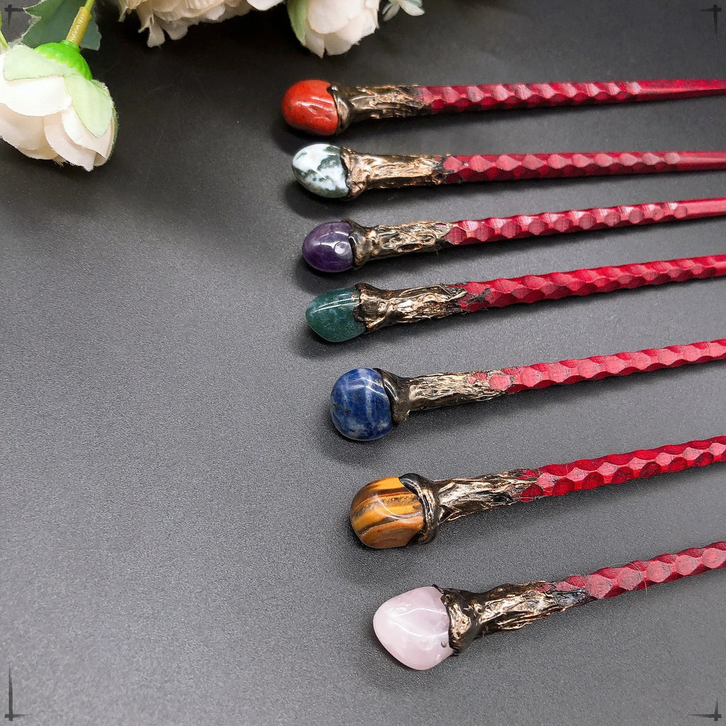 Détails des baguettes magiques avec diverses pierres telles que l'agate rouge et l'améthyste, disponibles chez Aemilia Mystica.