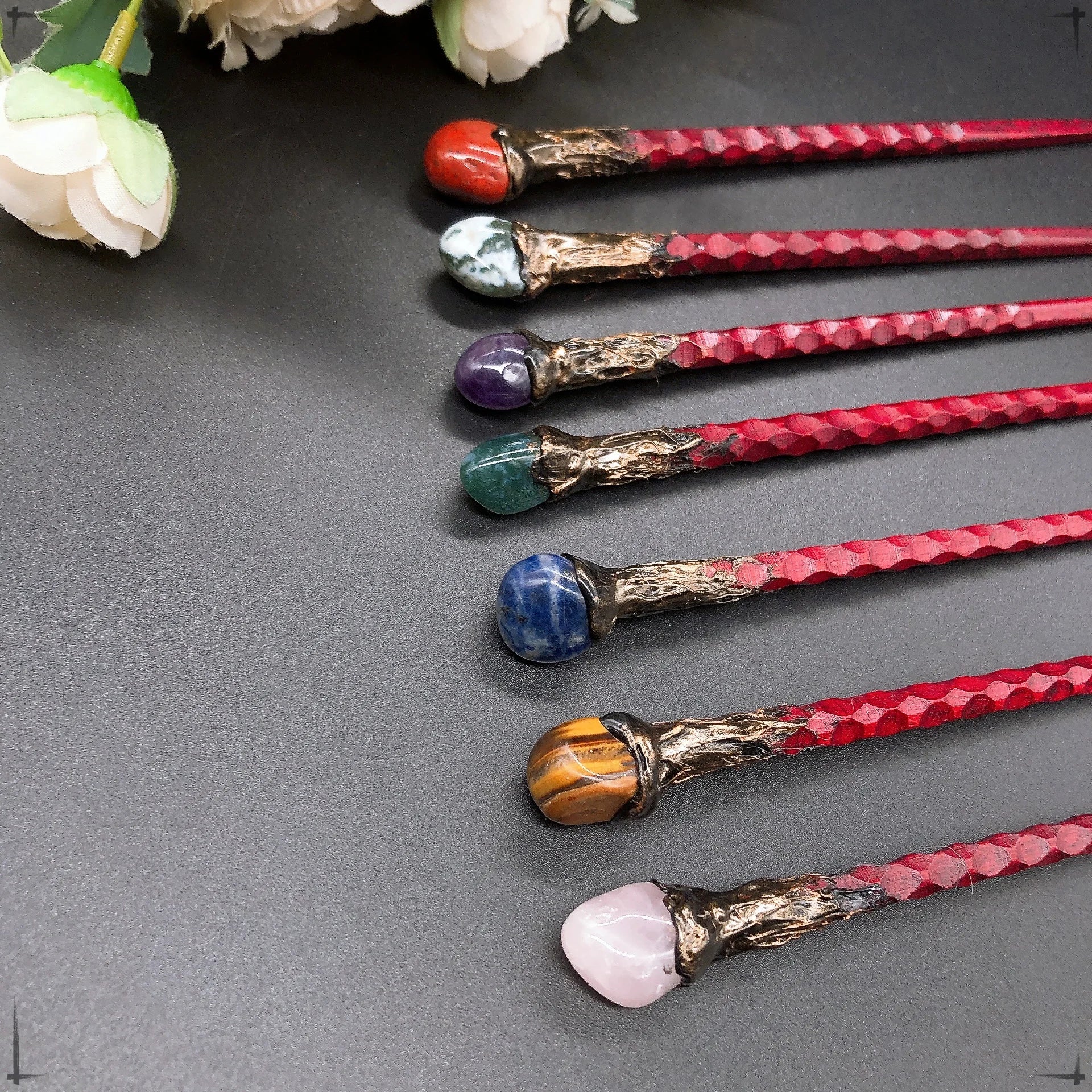 Détails des baguettes magiques avec diverses pierres telles que l'agate rouge et l'améthyste, disponibles chez Aemilia Mystica.