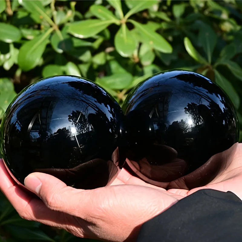 Deux boules en obsidienne noire naturelle polie – de 2 à 13 cm tenues à la main, affichant un éclat brillant, un choix parfait pour la décoration feng shui et comme cadeau pierre naturelle.