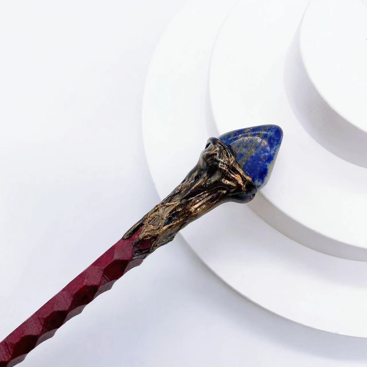 Bâton magique rouge décoré avec une pointe en lapis-lazuli, proposé par Aemilia Mystica. Idéal pour les amateurs de cristaux et de décoration magique.