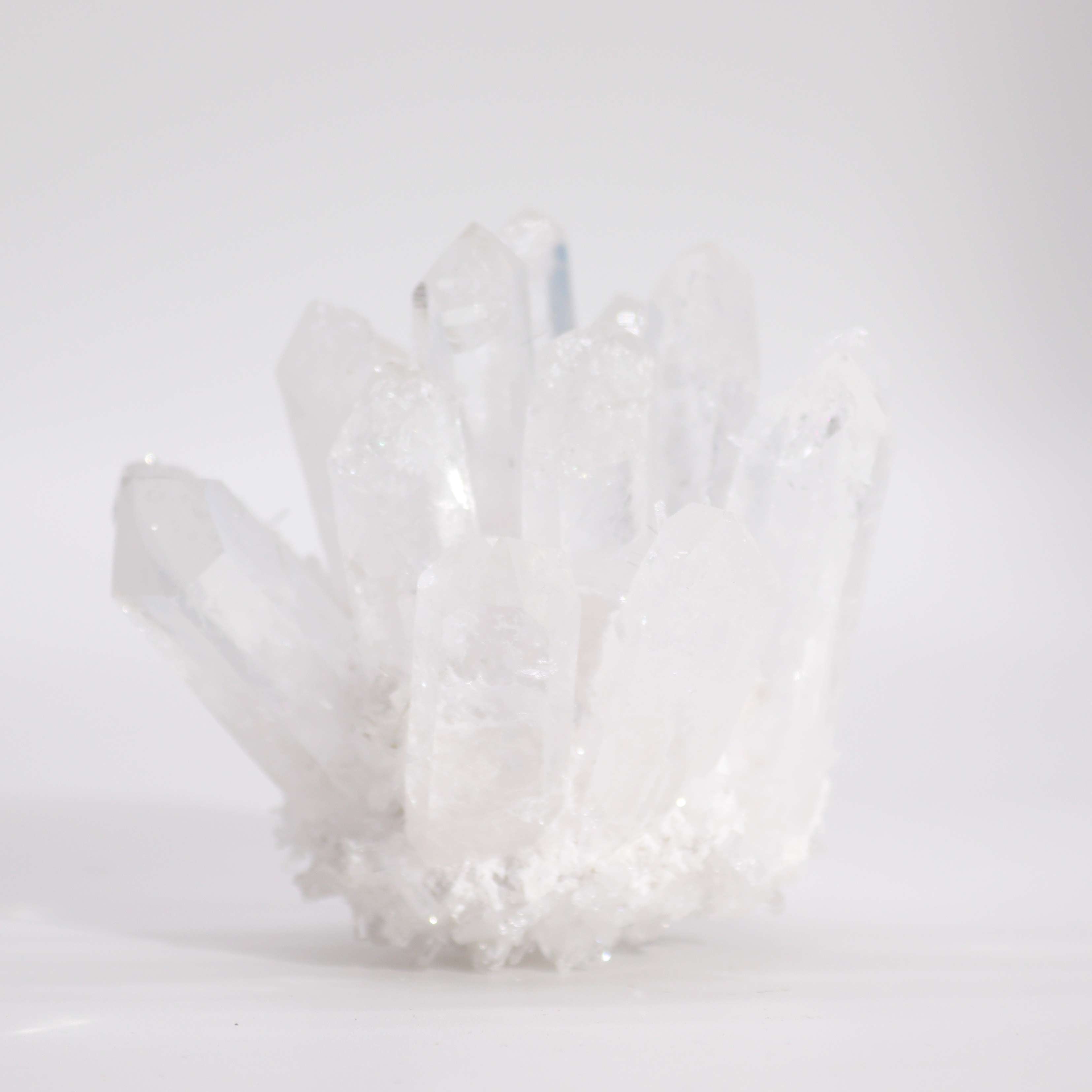 Amas de quartz clair naturel de 8 cm sur fond blanc, illustrant sa transparence et ses cristaux uniques. Produit par AWGifts Dropship.