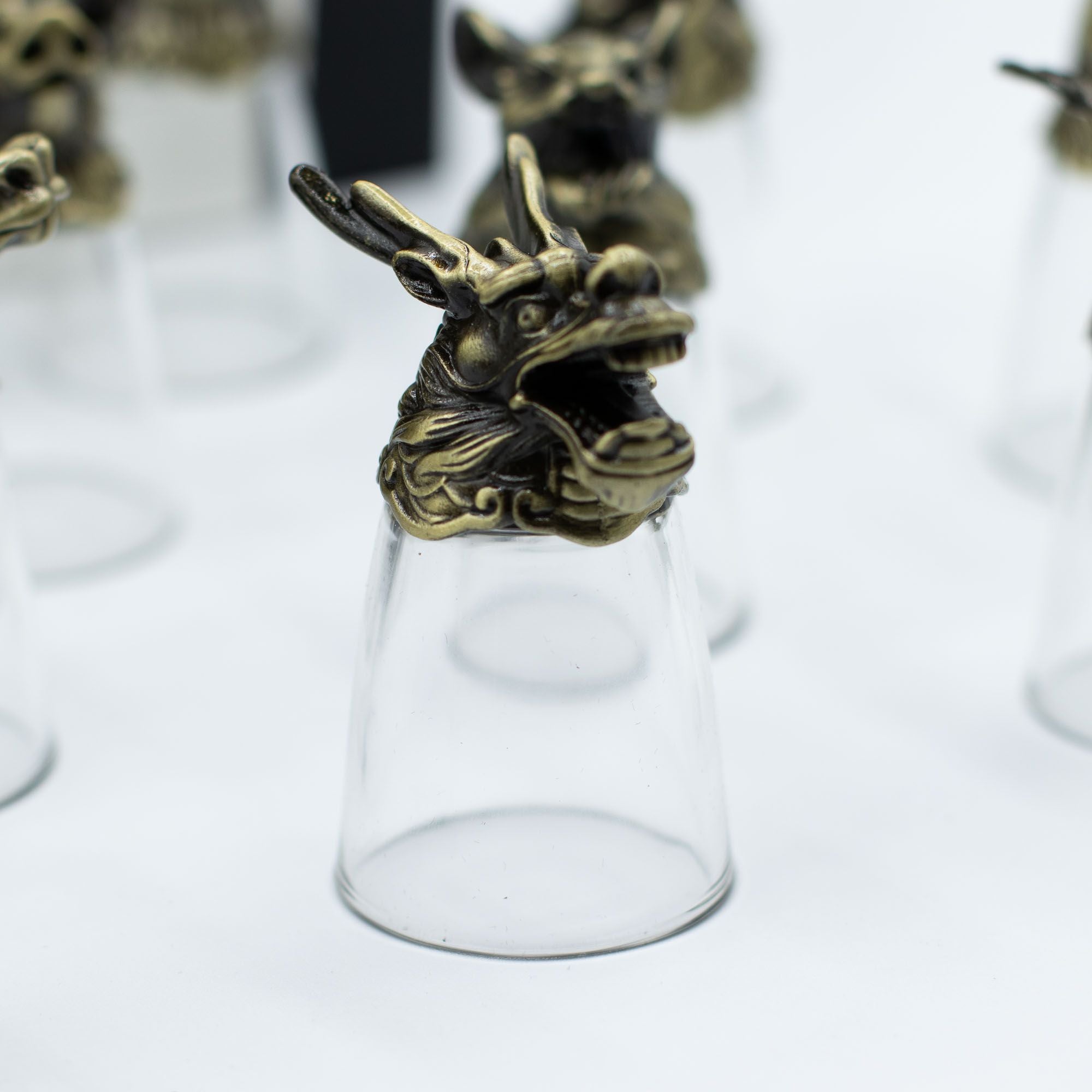 Focus sur un verre à shot en bronze antique, représentant un dragon dans le lot de 12 Bottom Up Shot Glasses (25ml). Parfait pour les amateurs de zodiaque chinois, ce verres à shot de 25 ml se distingue comme un accessoire de bar exceptionnel. Offrez ce coffret cadeau original qui allie culture et élégance, idéal pour les arts de la table.