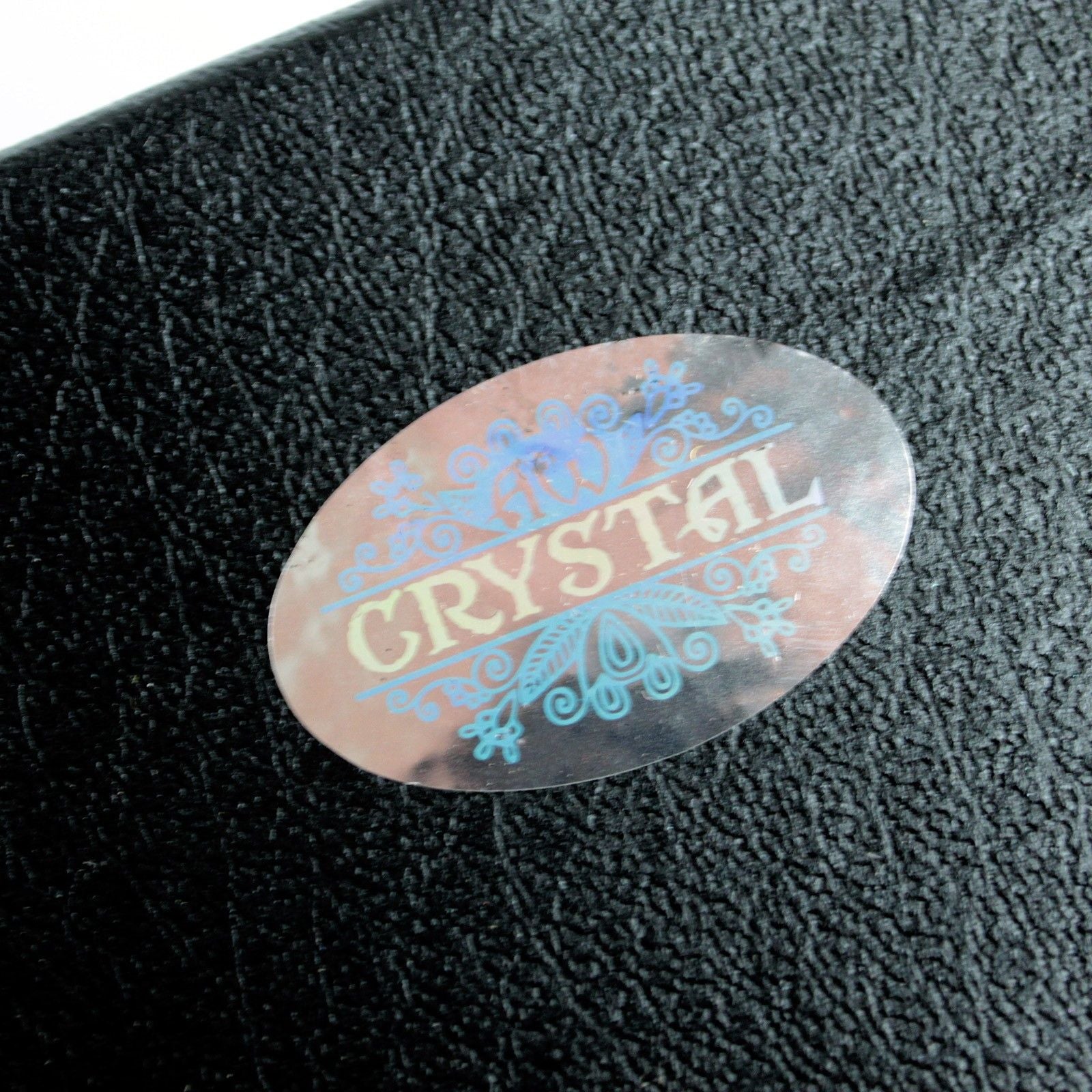 Détail d'un autocollant sur un support noir, illustrant le thème de la Boule de Cristal Sur Support - 100 mm. Ce produit, un accessoire spirituel prisé, est idéal pour embellir un autel ésotérique. Également un excellent choix pour ceux qui recherchent une boule de cristal comme élément décoratif et symbole dans leur décoration mystique et spirituelle.