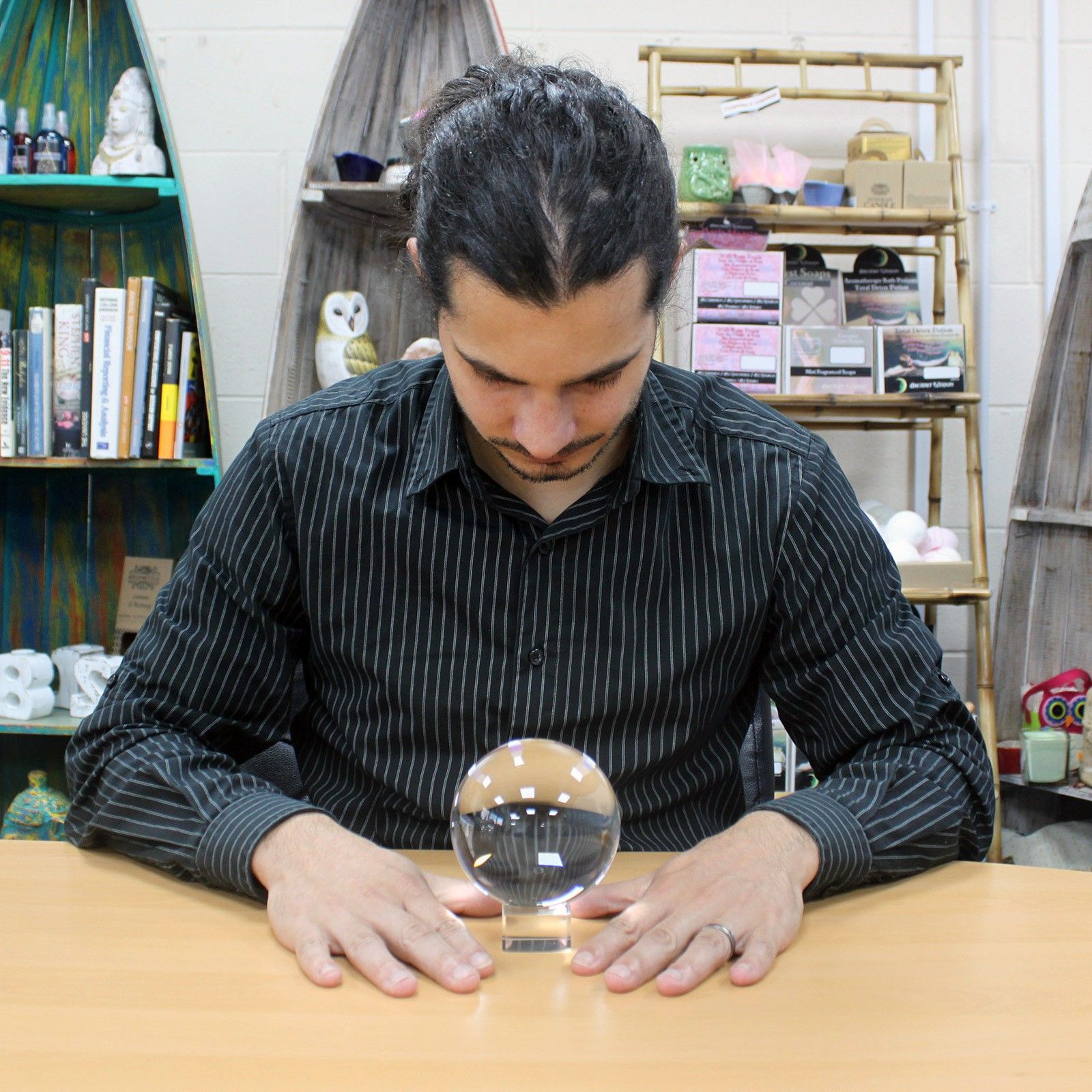 Un homme concentré devant une Boule de Cristal Sur Support - 100 mm, symbole fort du monde ésotérique. Cet accessoire spirituel sert aussi bien pour des rituels sur un autel ésotérique que pour une décoration mystique. La boule cristal 100 mm est parfaite comme objet de divination ou élément décoratif dans une ambiance spirituelle.