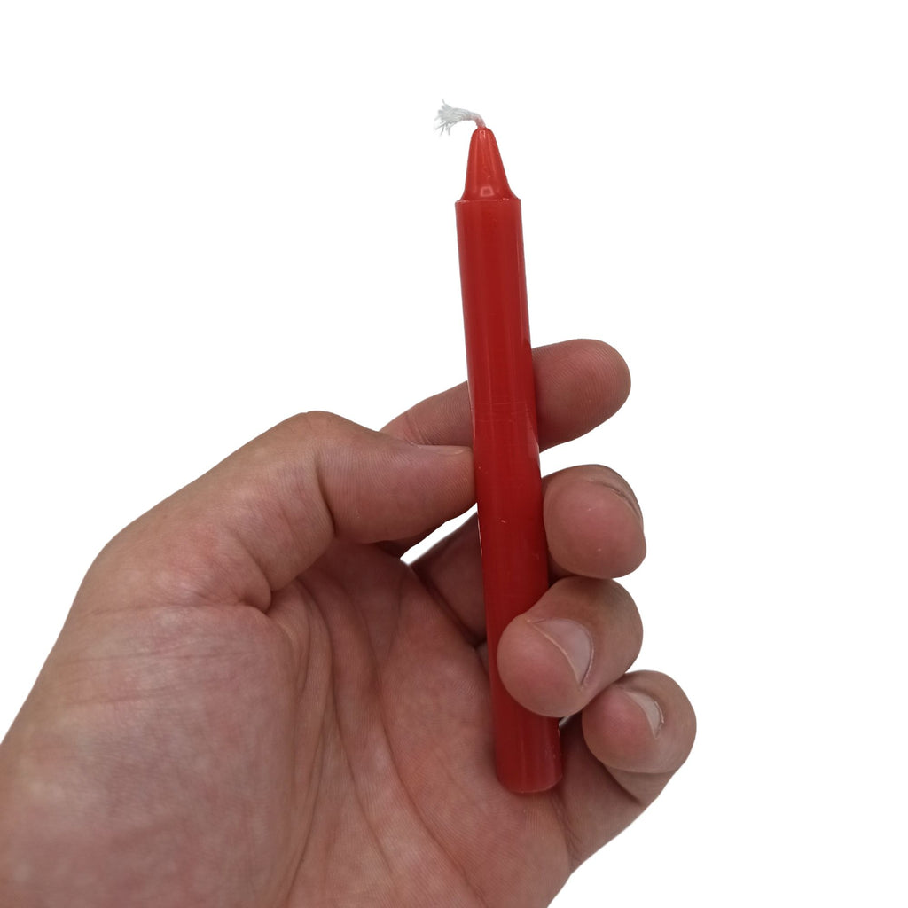 Bougies Manifest Magic (lot de 12) - rouge - chakra racine, montrant une bougie tenue dans une main, idéale pour la méditation et les pratiques spirituelles, favorisant la stabilité et la sécurité.