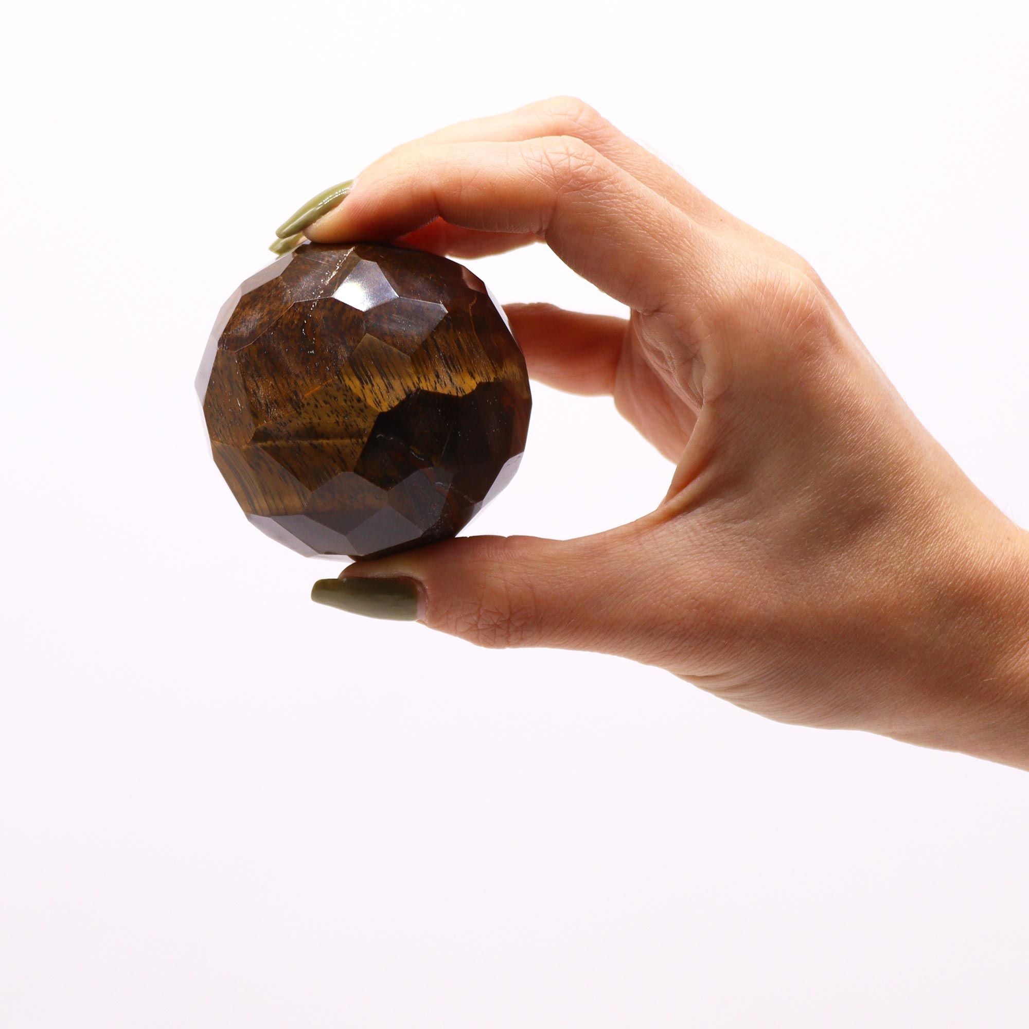 Gemstone Faceted Healing Ball & Stand - Tigereye. Tenez cette magnifique sphère en œil de tigre entre vos mains, symbole de guérison et d'ancrage. Cette boule œil de tigre naturelle est parfaite pour la lithothérapie et la protection énergétique, tout en servira de pièce maîtresse dans votre décoration spirituelle.