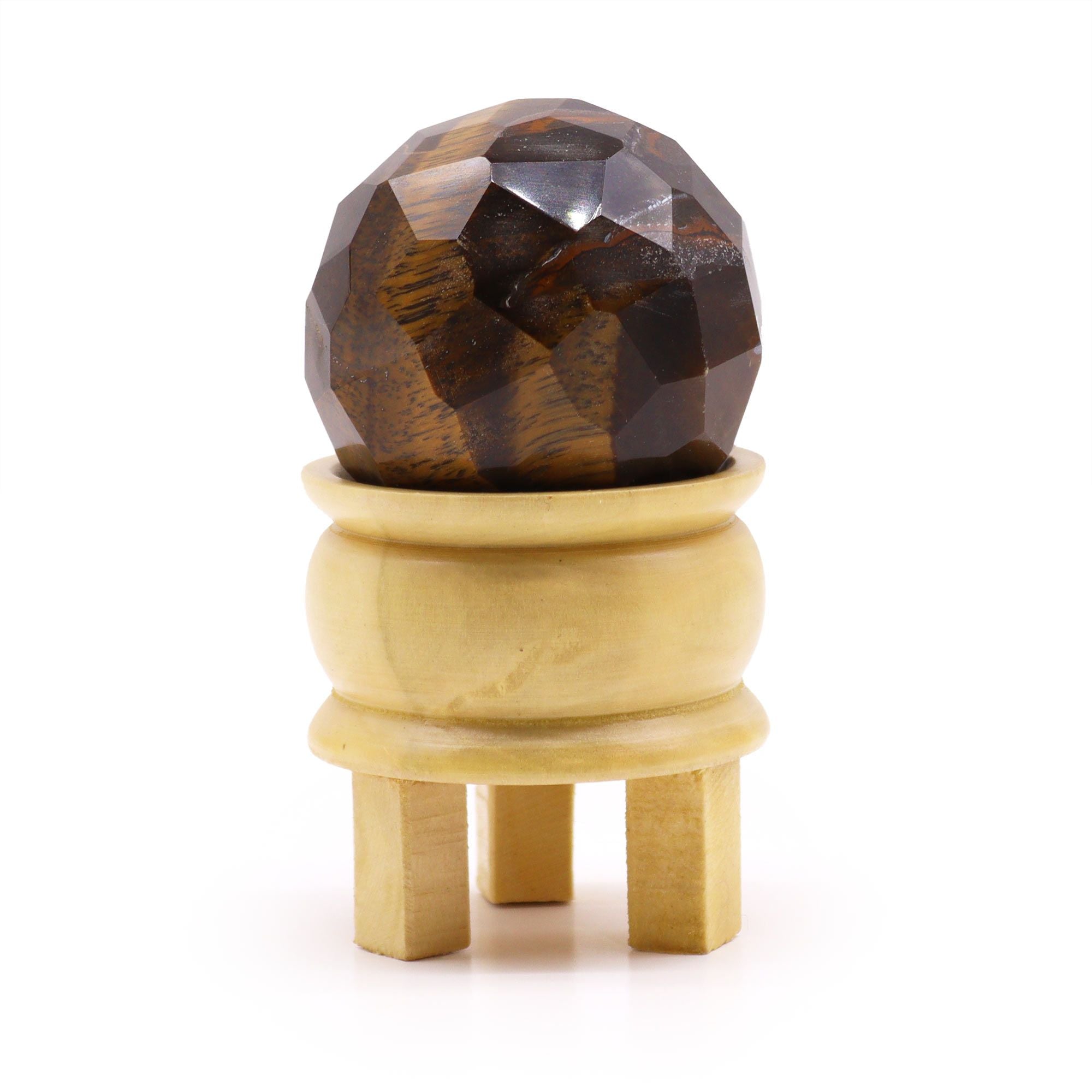 Gemstone Faceted Healing Ball & Stand - Tigereye. Cette magnifique boule de guérison en œil de tigre se dresse sur son support en bois, alliant esthétique et bien-être. Ajoutez cette sphère en pierre naturelle à votre collection pour bénéficier de la protection énergétique et renforcer votre confiance en soi.