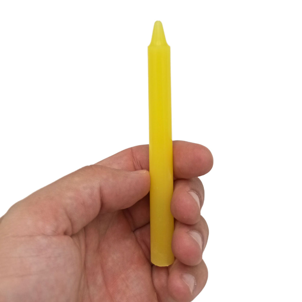 Bougies Manifest Magic, montrant une bougie jaune tenue dans une main, idéales pour le chakra du plexus solaire. Ces Bougies Jaune (lot de 12) - Chakra du Plexus Solaire apportent confiance et pouvoir personnel lors de pratiques spirituelles, méditation, et créent une atmosphère de sérénité et de transformation.
