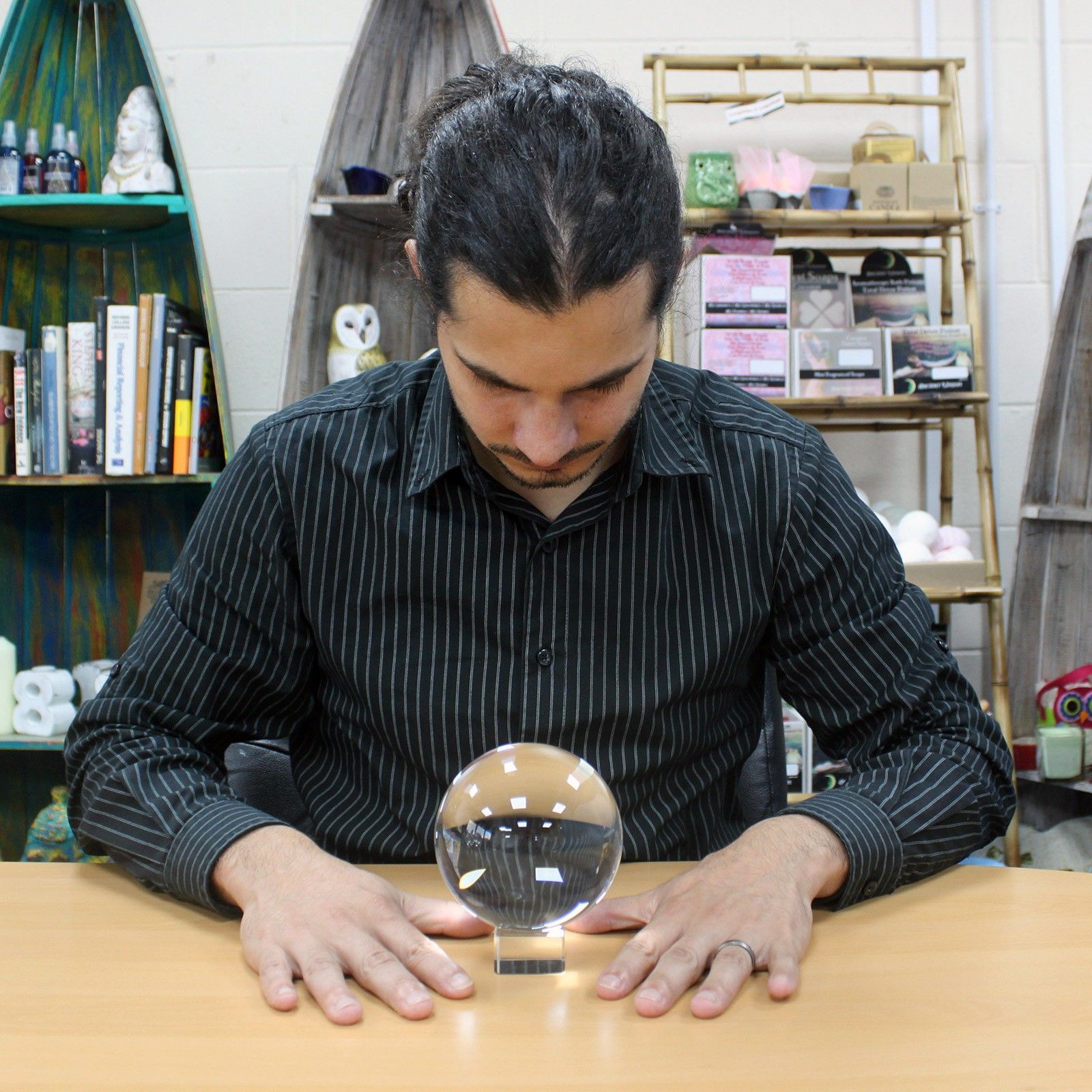 Un homme se concentre sur une Boule De Cristal Sur Support - 110 Mm, symbole d'accessoire spirituel, idéale pour un autel ésotérique. Cette boule de cristal 110 mm est une décoration mystique, parfaite dans un espace de méditation ou comme objet de divination.