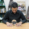 Une personne en train de consulter une boule de cristal sur support de 130 mm, symbole d'accessoire spirituel et d'objet de divination, parfait pour un autel ésotérique ou une décoration mystique. Cette boule de cristal est un bel élément décoratif apportant une ambiance spirituelle et ésotérique.