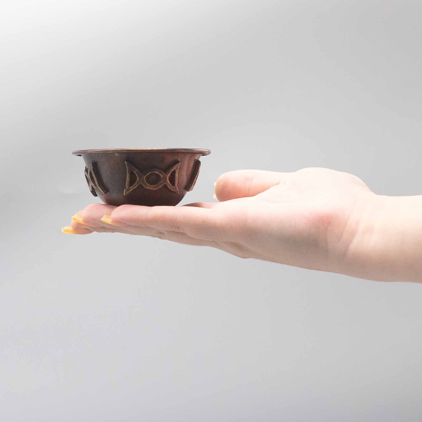 Calice Rituel en Cuivre Antique Triple Lune dans la main, montrant sa taille compacte et sa praticité. Ce calice rituel est parfait pour les offrandes et comme gobelet rituel sur votre autel. Son design évoque la déesse et le féminin sacré.