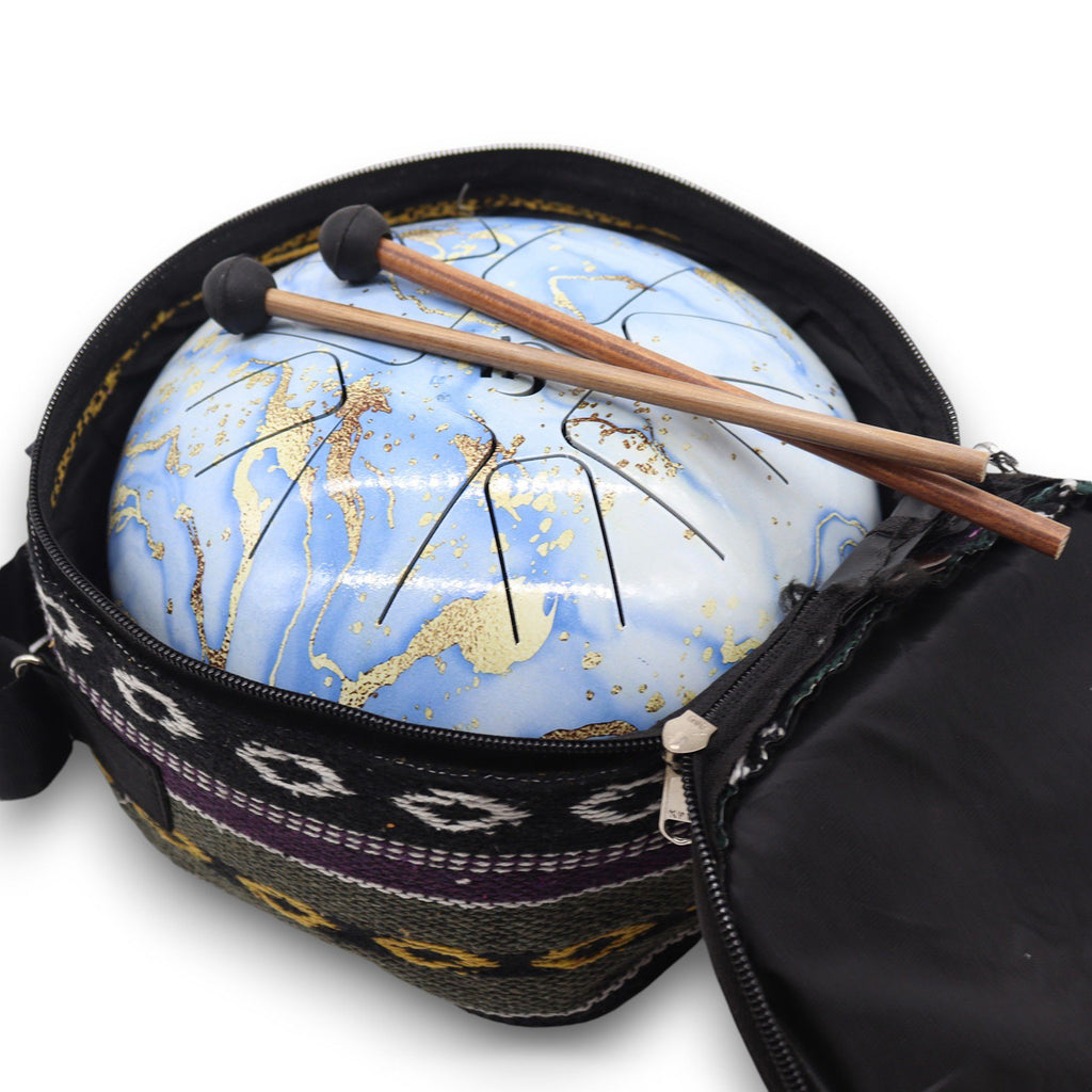 Le Steel Tongue Happy Drum Bleu Ciel en Acier – 22 x 18 cm est soigneusement rangé dans son sac de transport, révélant ses baguettes. Cet instrument de relaxation est idéal pour les séances de méditation et de sonothérapie.