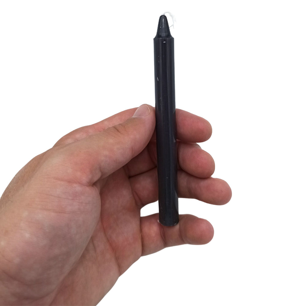 Bougies Manifest Magic (lot de 12) - Noir - Transformation, une bougie noire tenue à la main, parfaite pour accompagner votre pratique de méditation, favorisant sérénité et nouveaux départs pendant 90 minutes.