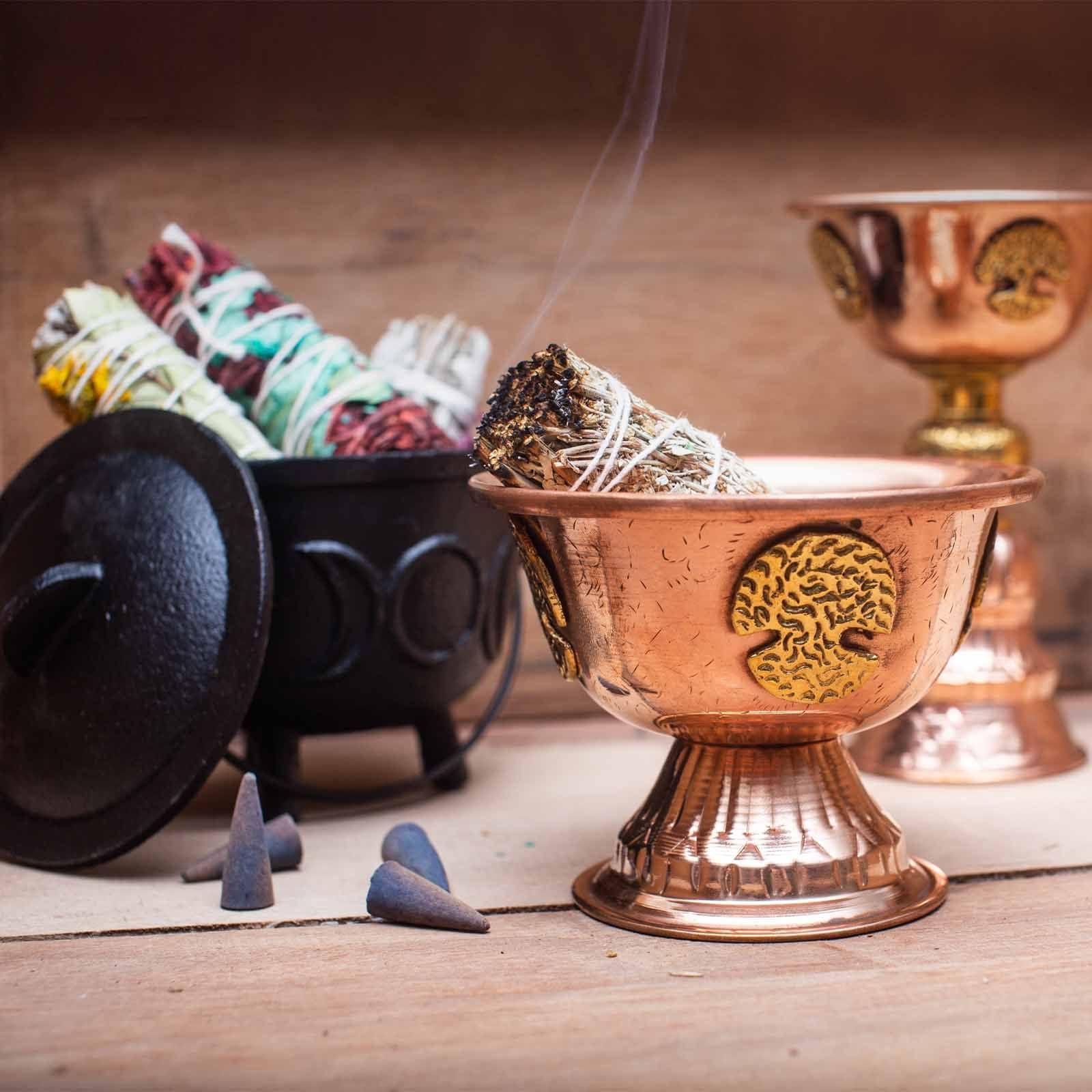La Coupe Rituelle en Cuivre avec Arbre de Vie 10x15cm aux côtés d'éléments rituels, illustrant son utilisation lors de cérémonies. Cette coupe en cuivre est parfaite pour les offrandes, tout en ajoutant une dimension décorative spirituelle. Un bel objet ésotérique à intégrer dans votre collection d’accessoires rituels.