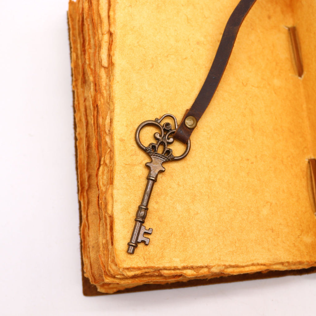 Gros plan sur la clé du carnet en cuir huilé avec clé - Pour Grimoire spirituel 200 pages, accentuant son détail vintage. Ce carnet cuir de 13 x 18 cm avec 200 pages est parfait pour personnaliser ses rituels et exprimer sa créativité.