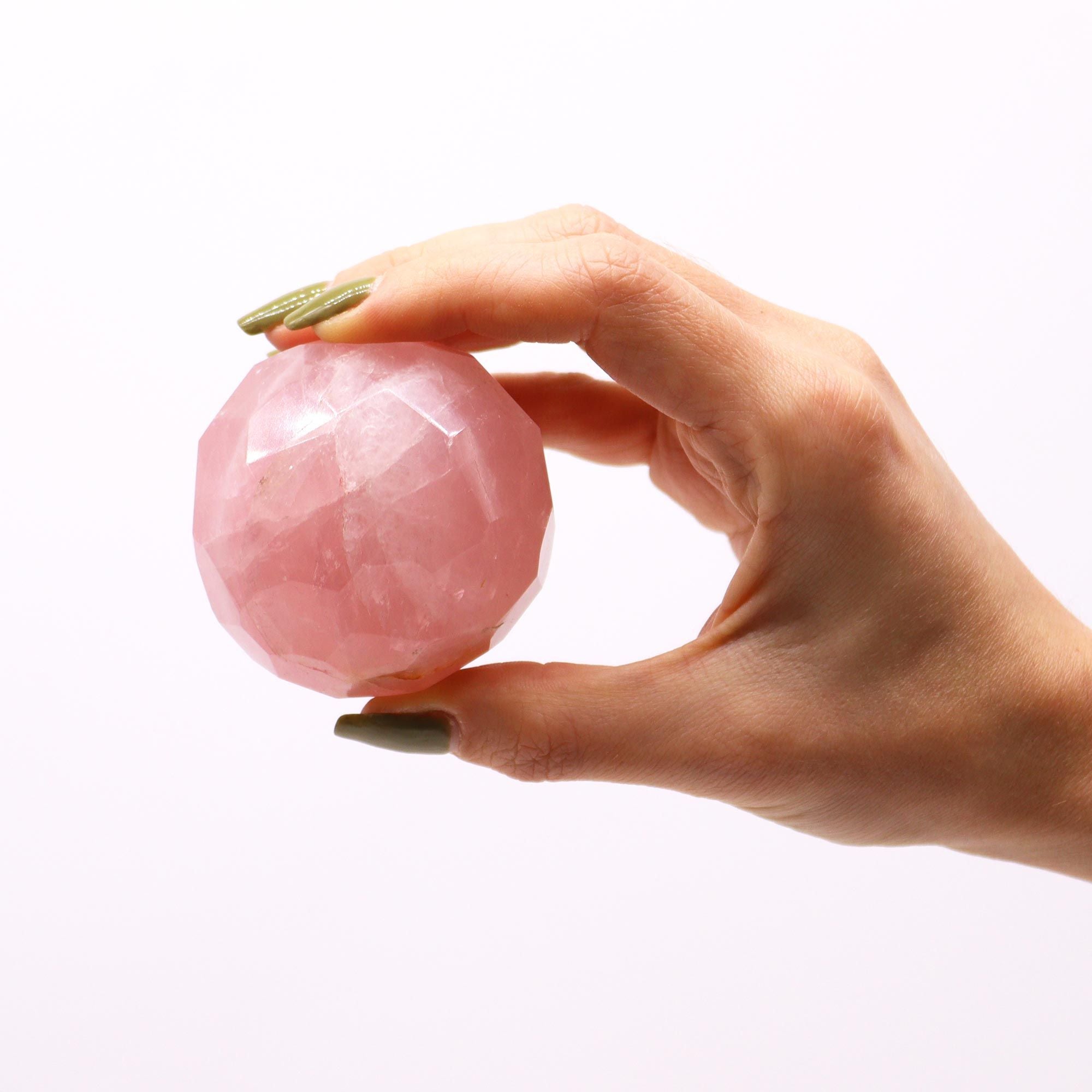 Boule De Guérison En Quartz Rose - La main tenant un cristal naturel de quartz rose. Avec cette sphère en pierre naturelle, profitez de la lithothérapie, en favorisant l'amour et la compassion en vous, et améliorez votre bien-être spirituel.
