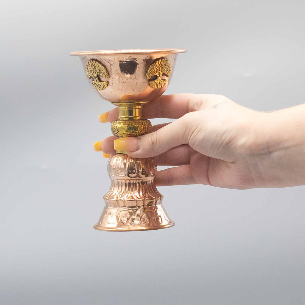 La Coupe Rituelle en Cuivre avec Arbre de Vie 10x15cm, tenue dans la main, souligne sa légèreté et sa facilité d'utilisation. Cet accessoire d’autel est une magnifique addition aux rituels spirituels, symbolisant la connexion et l’équilibre. Un choix idéal pour ceux qui recherchent des objets ésotériques en cuivre antique.